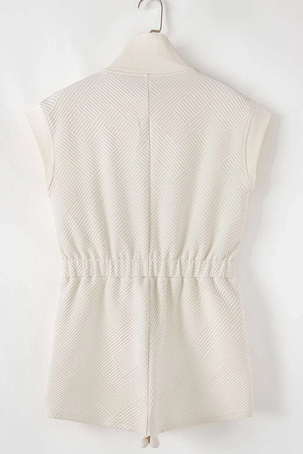 Cream textured zip-front romper, back view with yoke seams and short legs