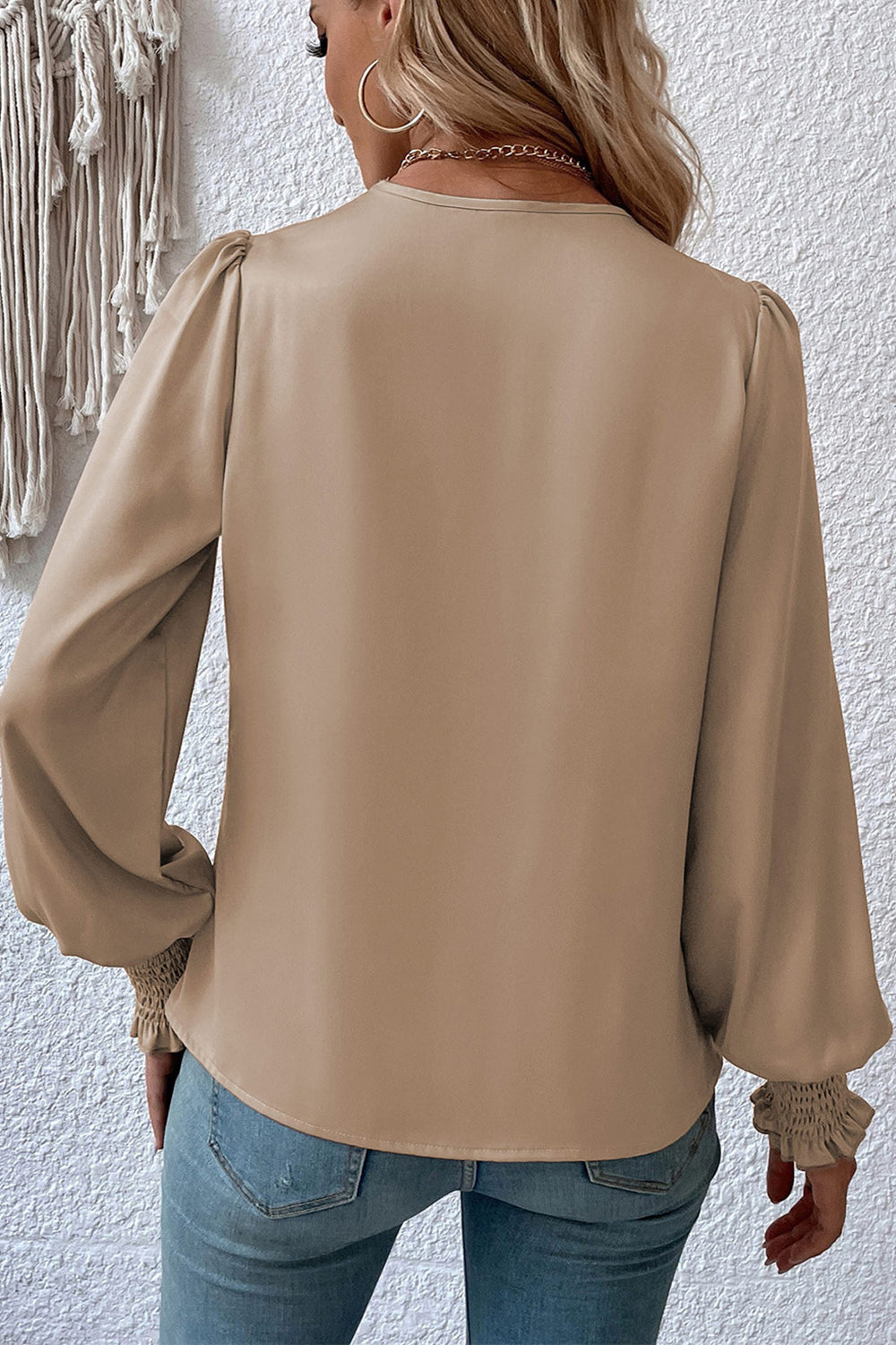 Khaki surplice-neck lantern sleeve blouse from the back with gathered cuffs.
