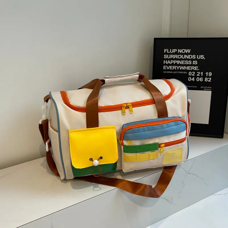 Beige travel duffle bag with orange trim, brown handles, and multiple zip pockets
