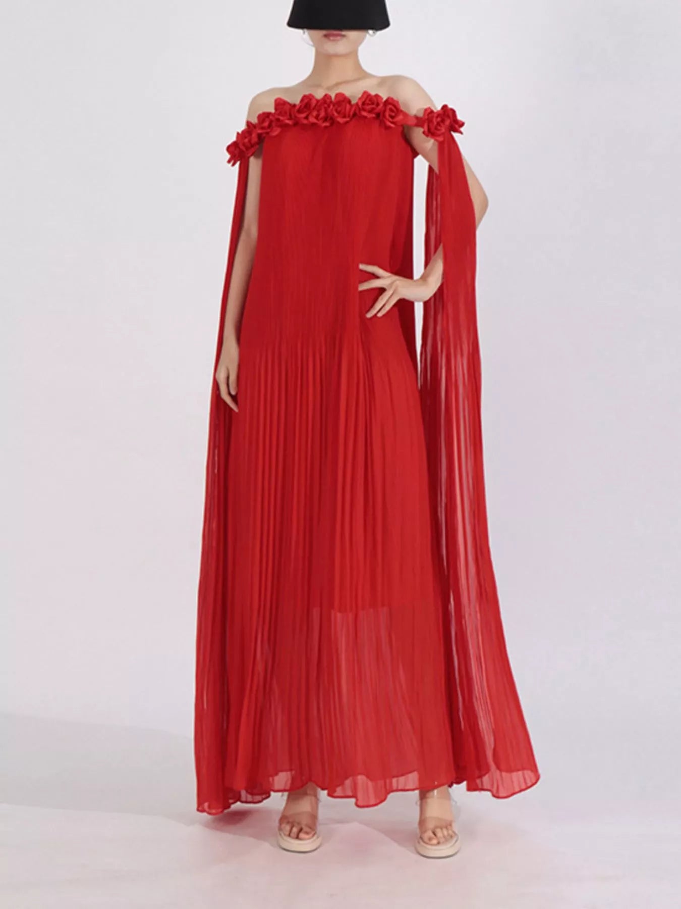Red off-shoulder maxi dress with floral rosette neckline and pleated, flowing skirt.