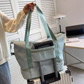 Light teal nylon duffel bag on rolling suitcase, with front organizer pouch