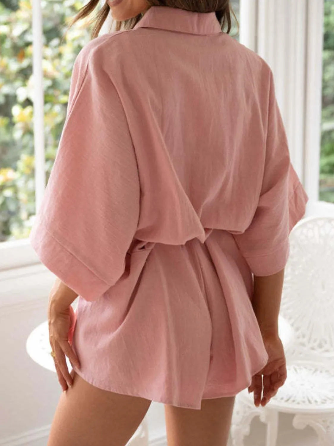 Dusty pink collared half-sleeve romper in back view with tied waist detail