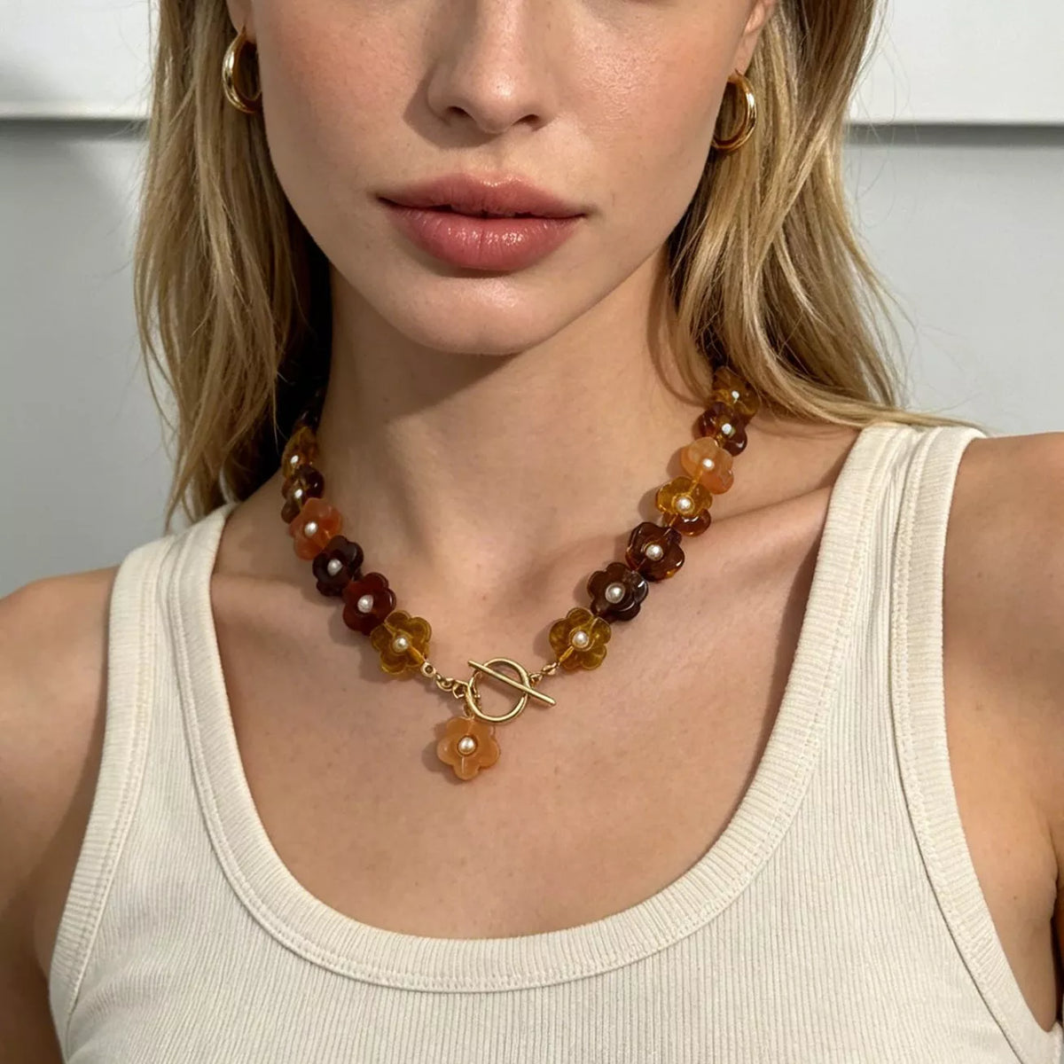 Gold beaded necklace featuring alternating amber and dark brown resin flower beads