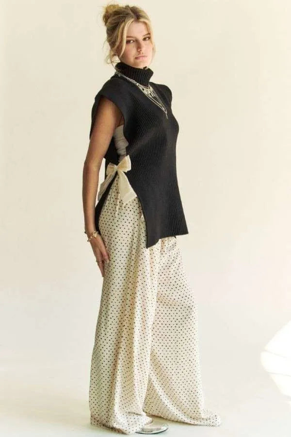Black sleeveless turtleneck knit top with side bow and asymmetric back hem