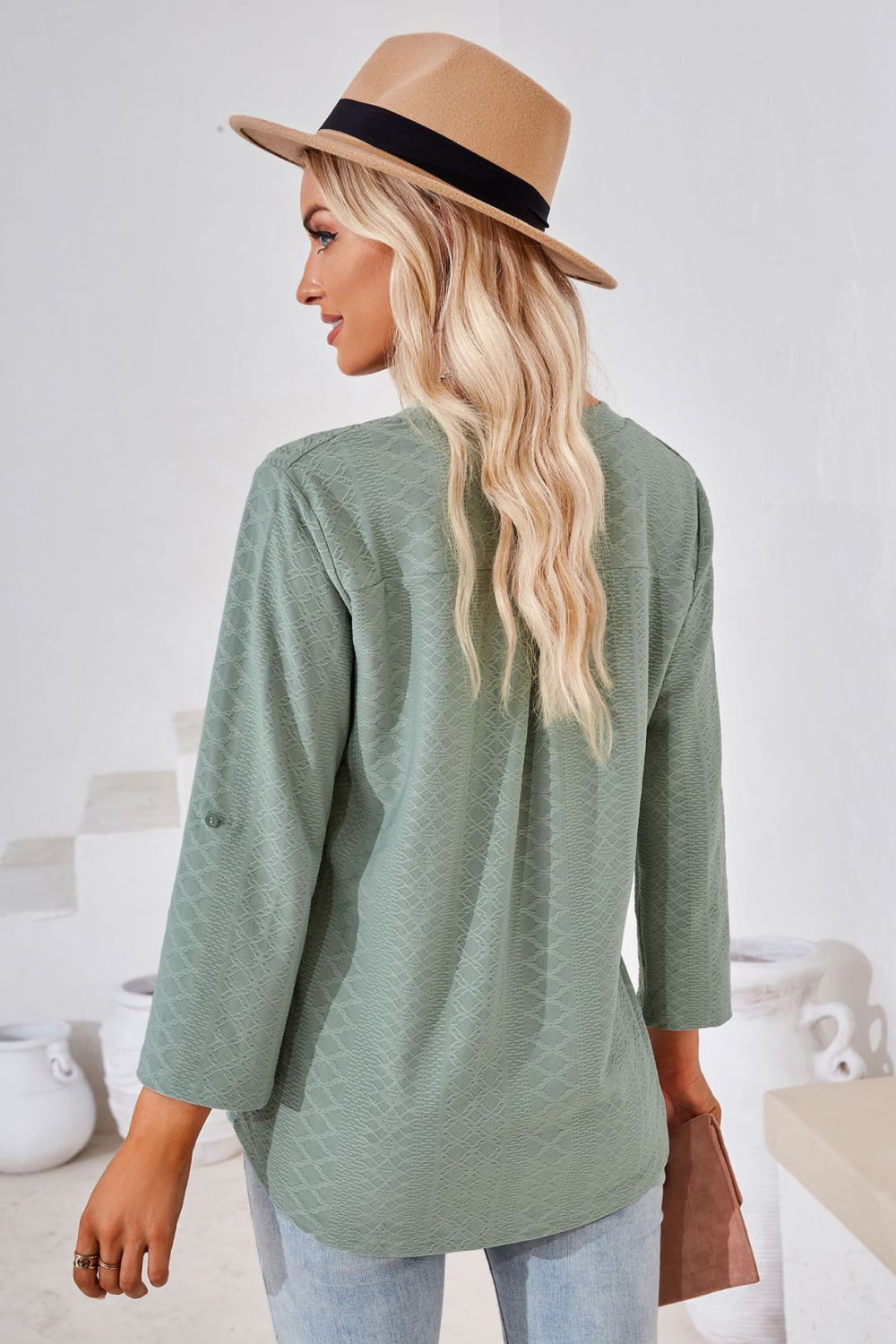 Light sage green V-neck blouse with roll-tap sleeves, textured woven look.