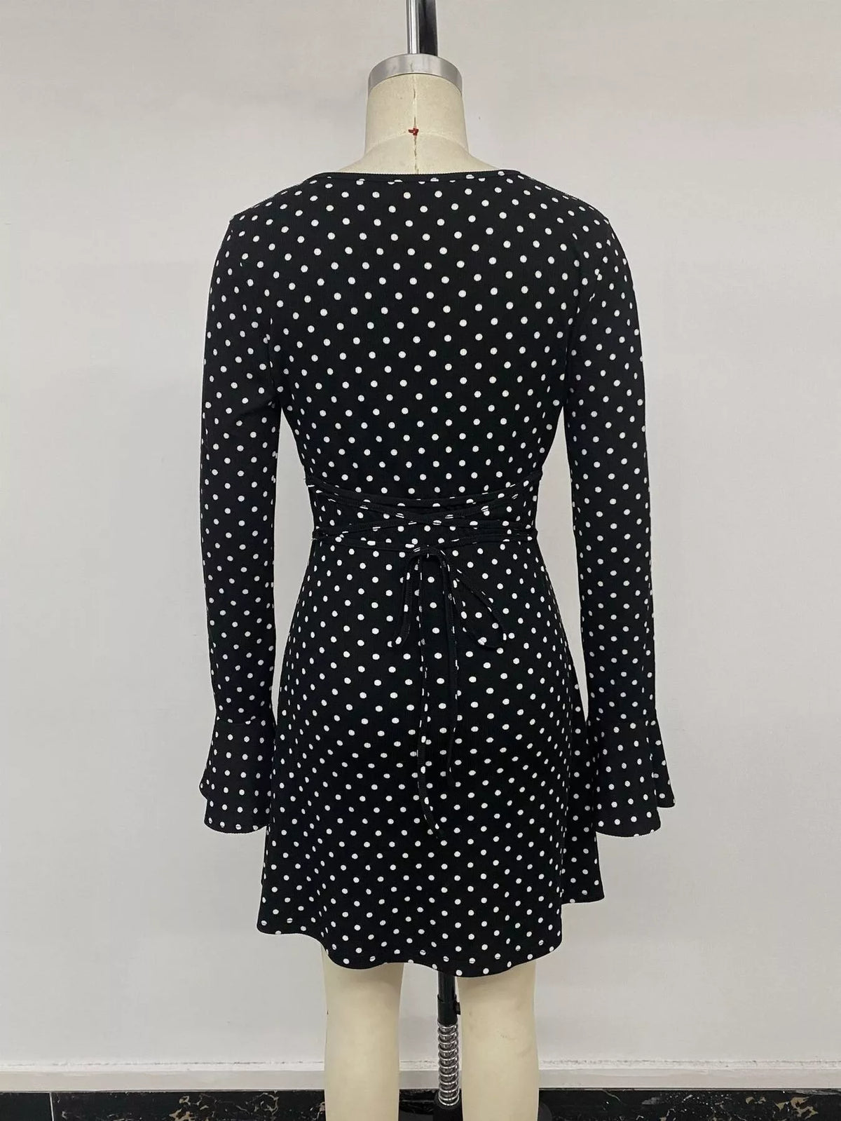 Black polka dot long sleeve mini dress, back view with gathered waist