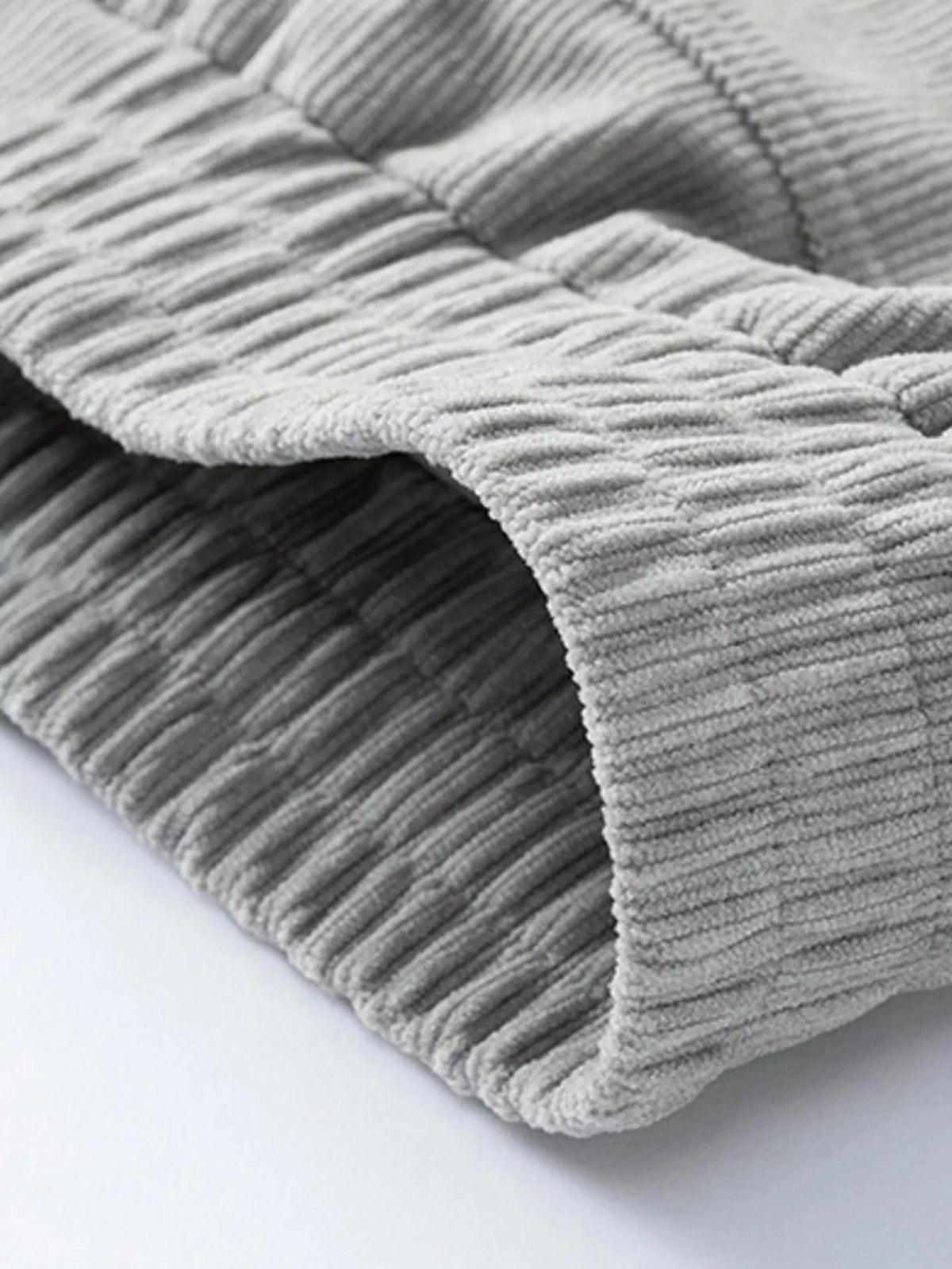 Gray corduroy fabric with raised rib texture, folded sleeve edge