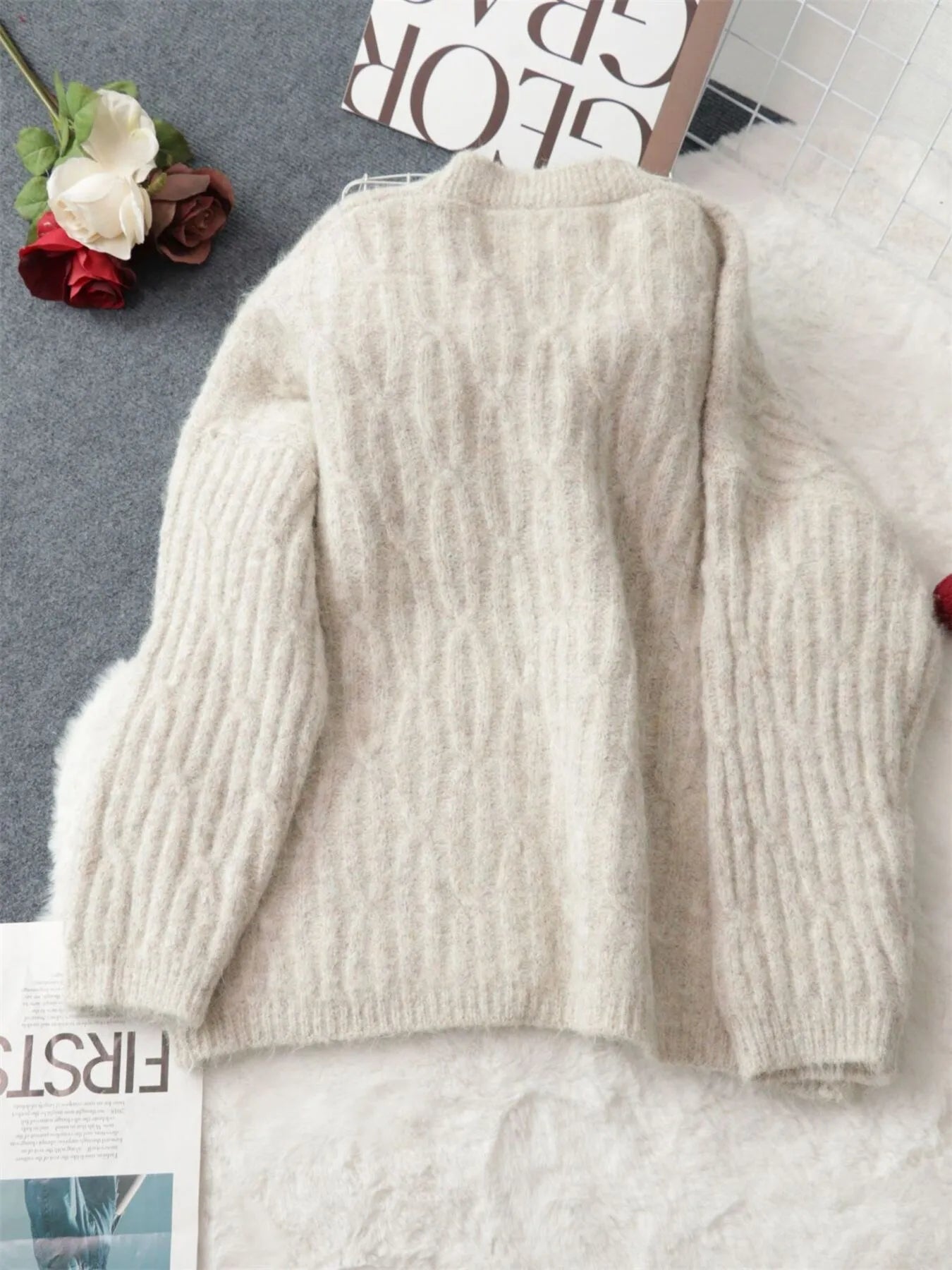 Cream cable knit cardigan laid flat, showing back length and ribbed cuffs