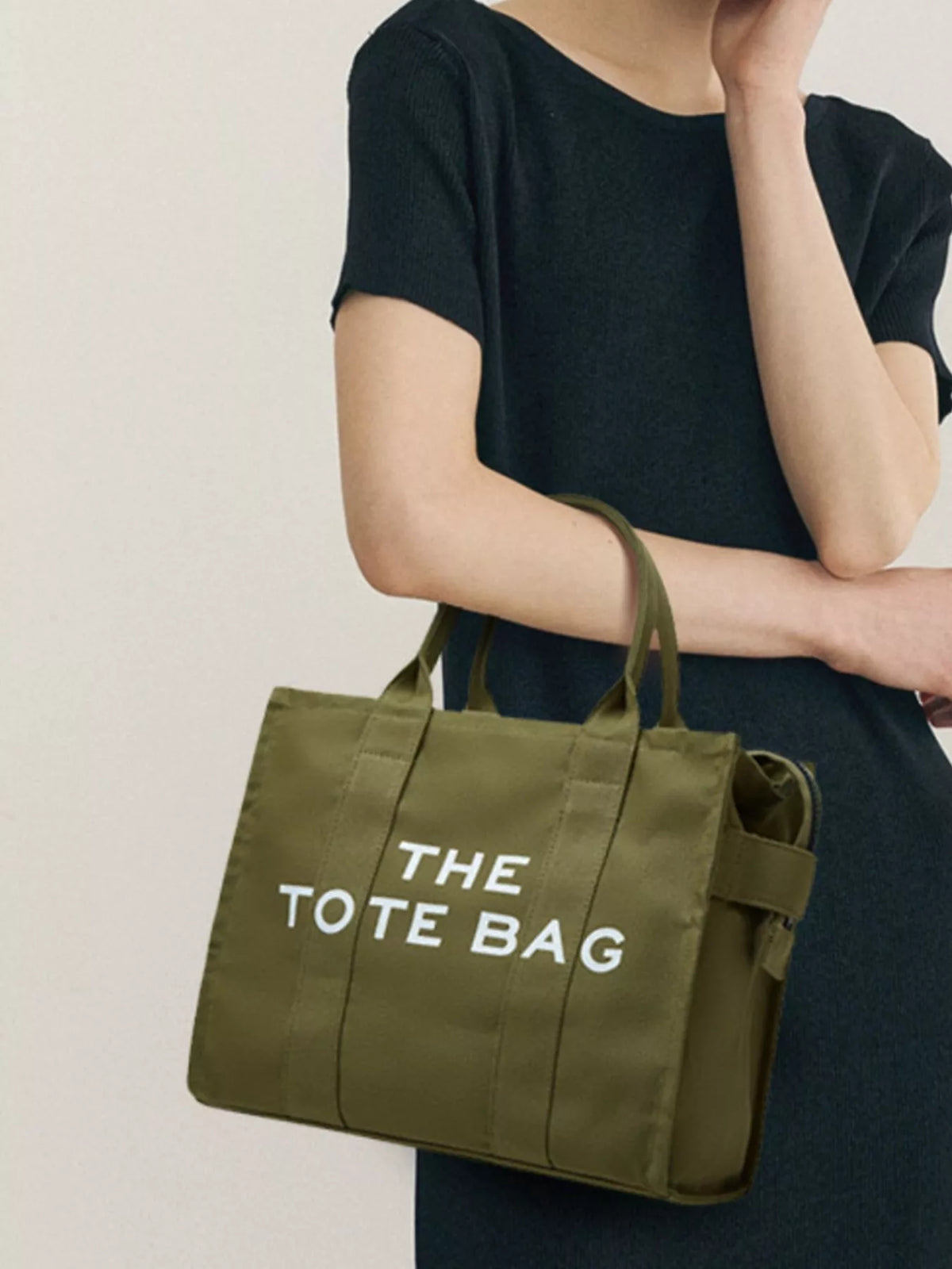 Army green canvas tote bag with “THE TOTE BAG” text, side view with short strap