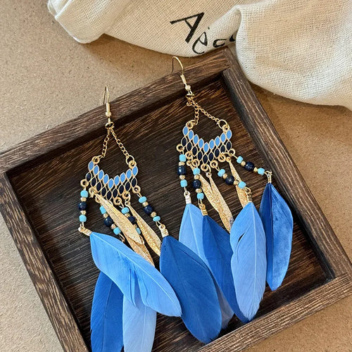 Gold-tone dangle earrings with blue beadwork and layered blue feather drops