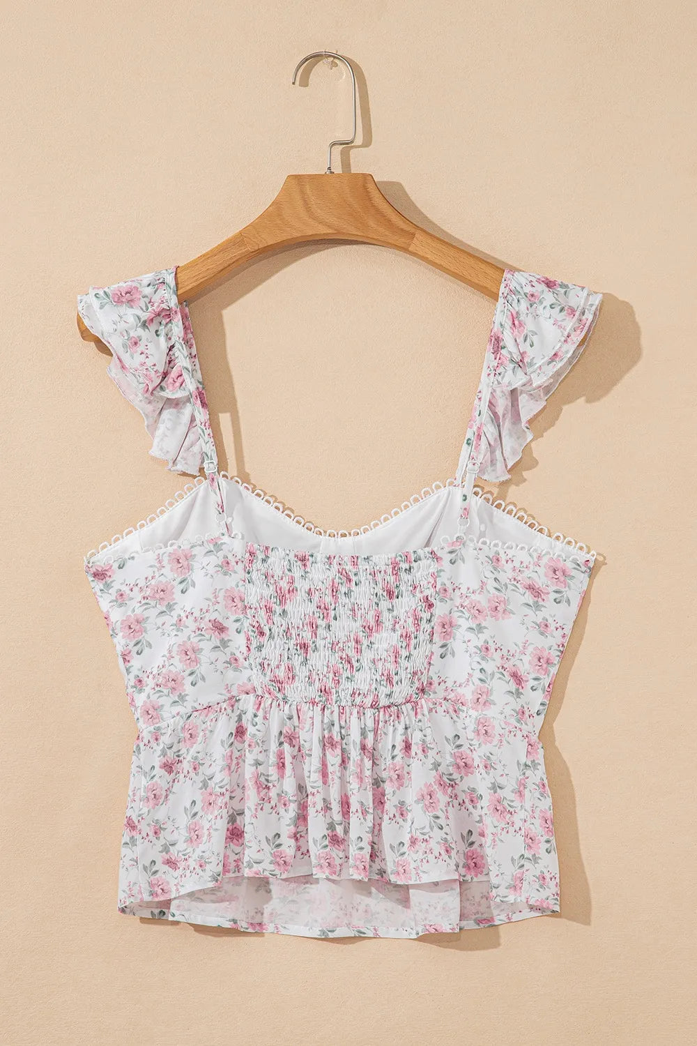 Back of floral peplum tank top on hanger with blush pink floral print and ruffle straps