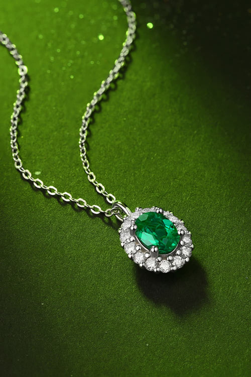 Sterling silver necklace with green emerald halo pendant, side angle on chain