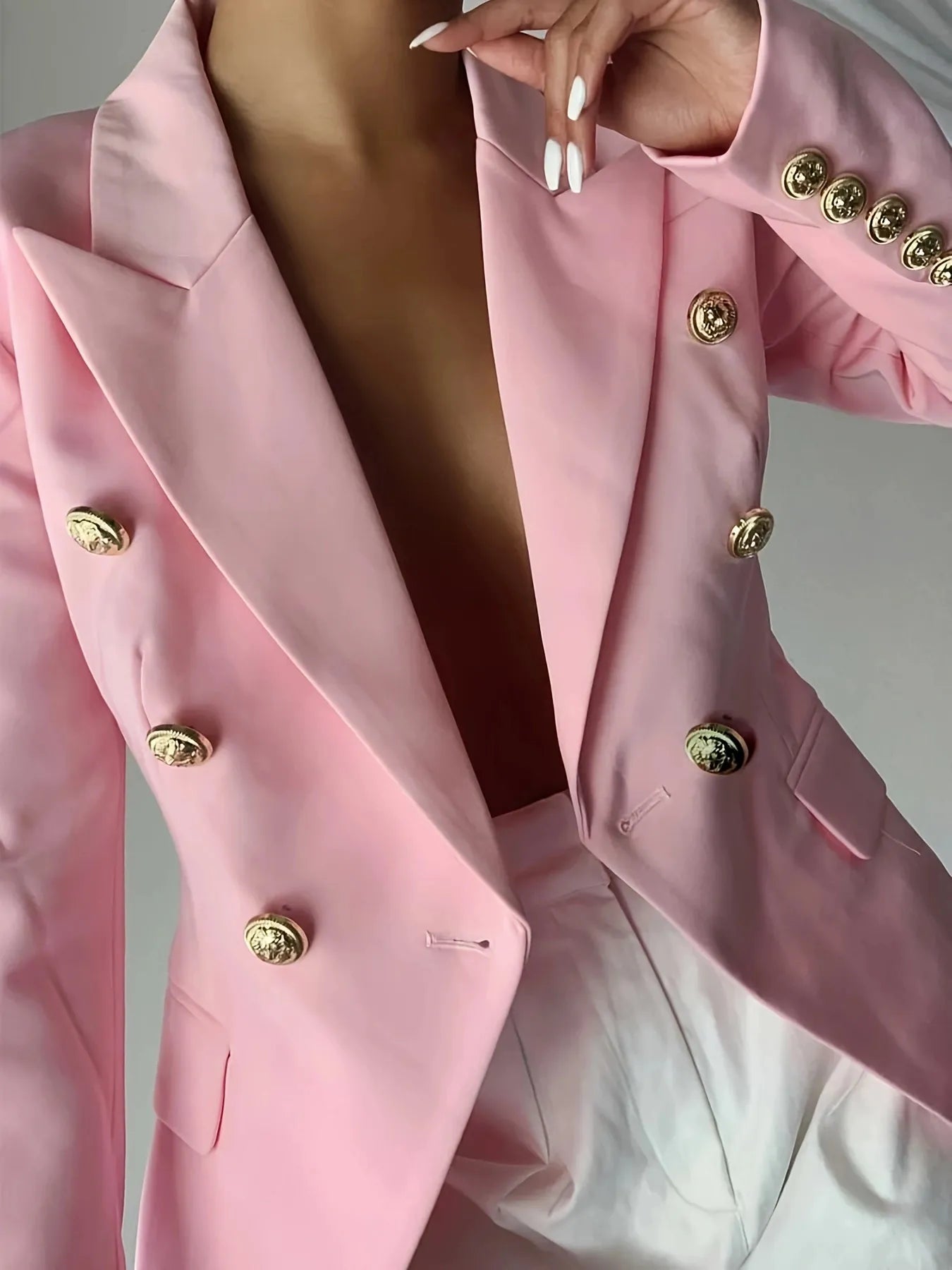 Pink blazer with gold decorative buttons, notch lapels, and flap pockets