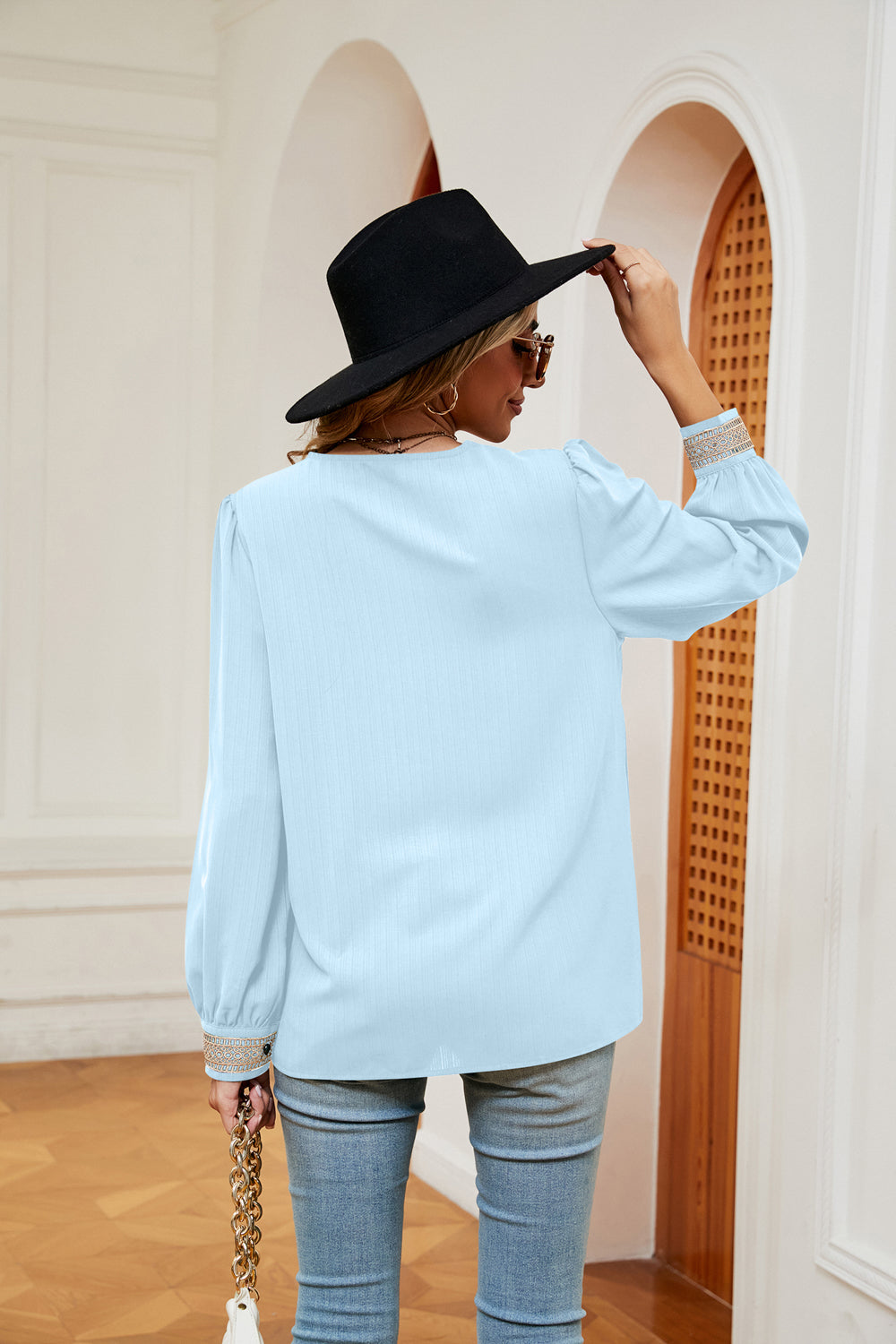 Light blue blouse with contrast cuff trim and long puff sleeves, back view