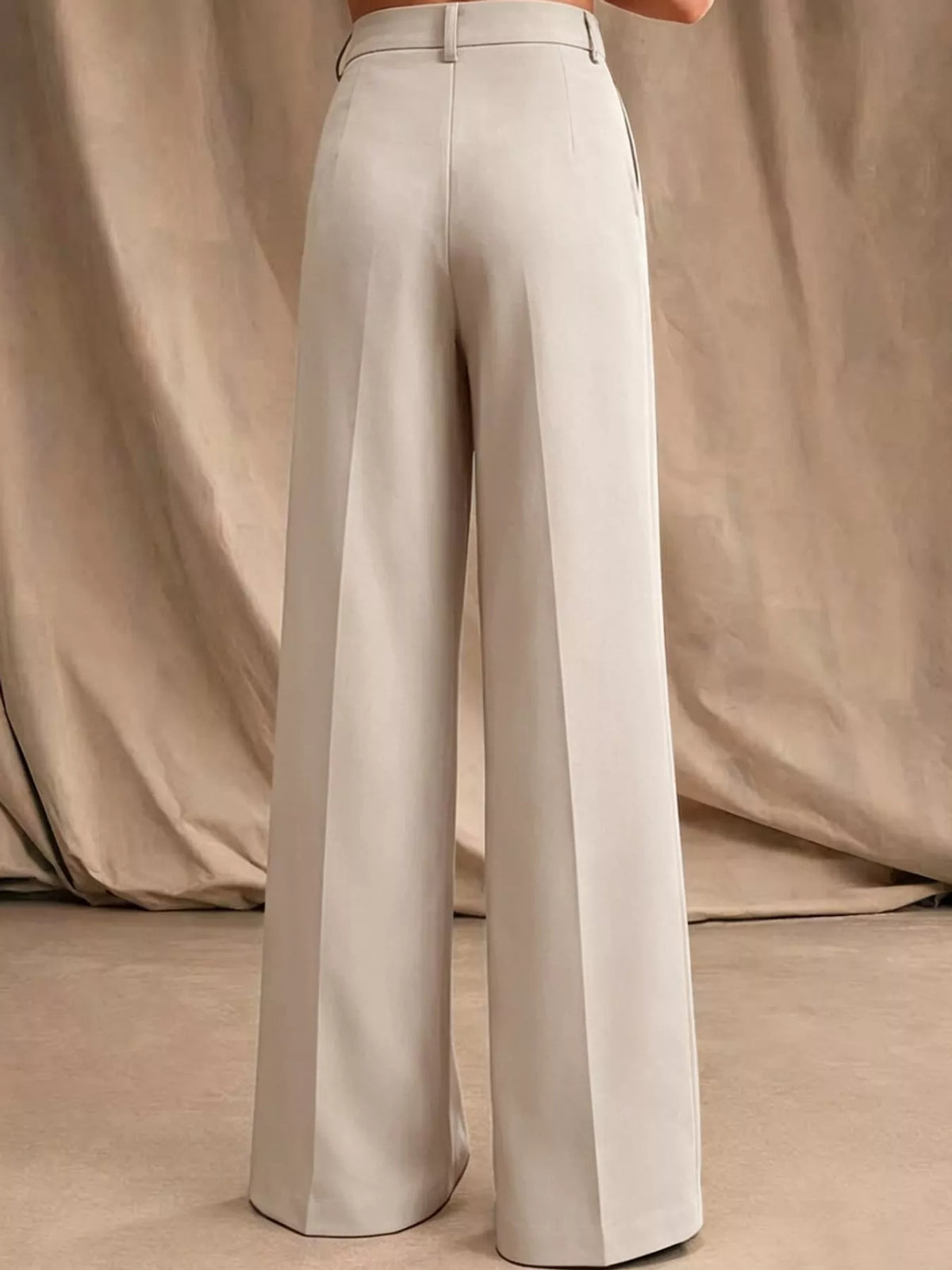 Cream high-waisted pleated wide-leg pants with belt loops and front button closure
