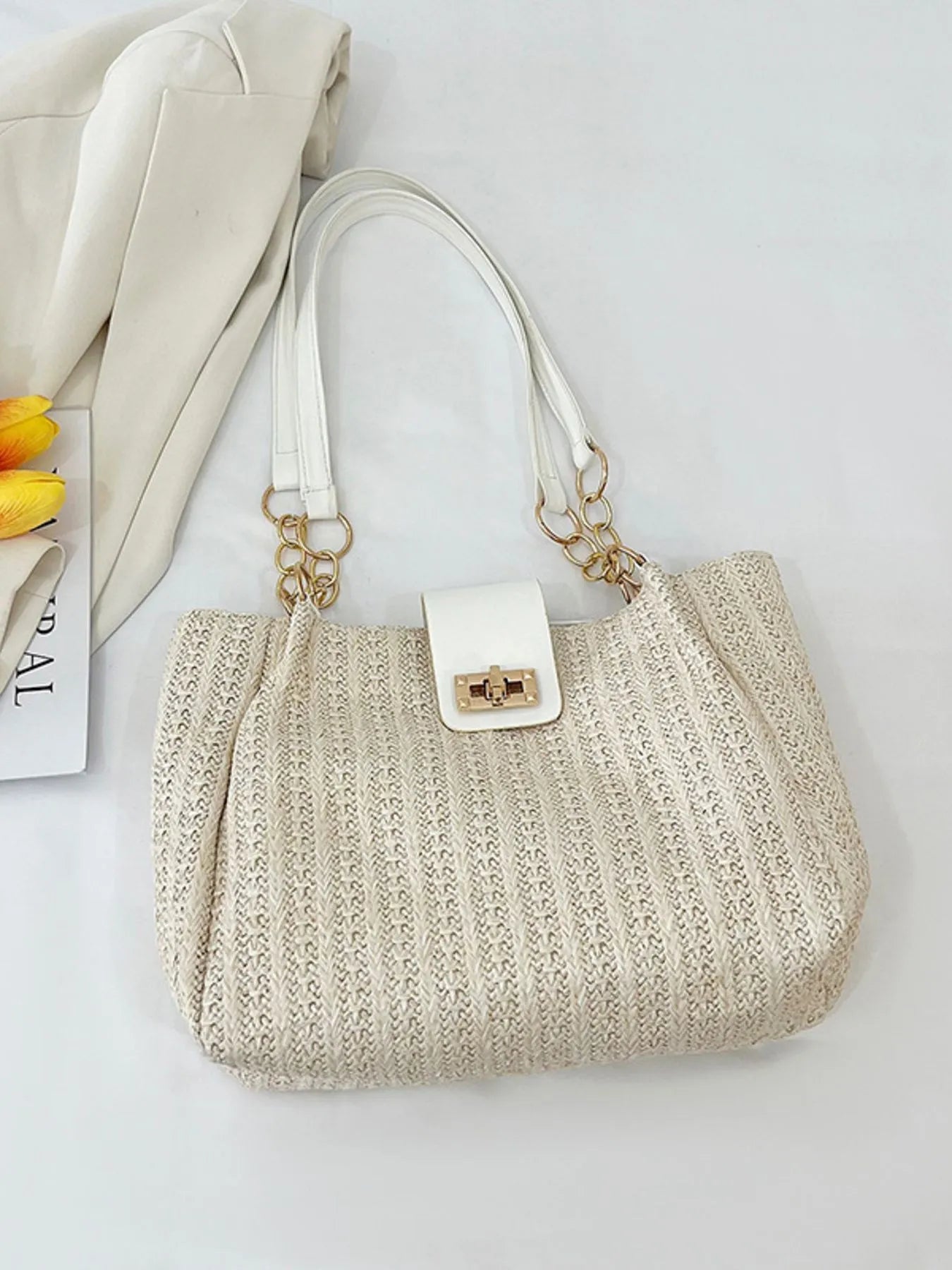 Woven straw shoulder bag in beige with white top handles and gold chain clasp