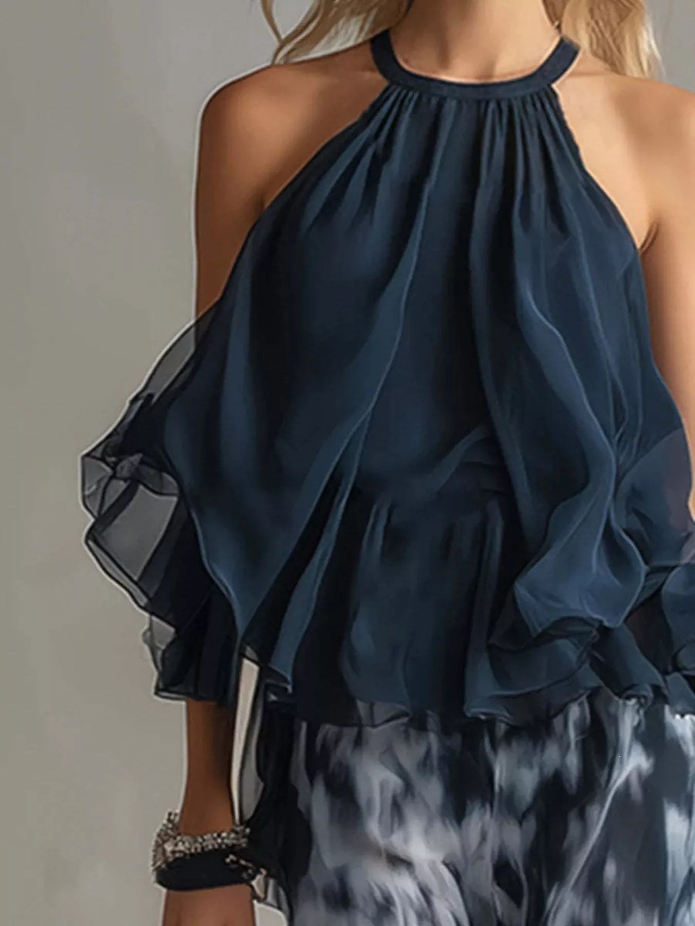 Dark blue halter ruffle top with layered neckline detail over tie-dye pants.