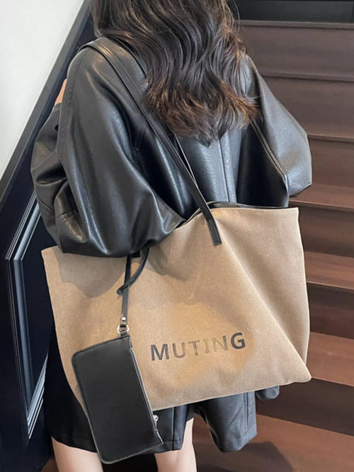Tan canvas tote shoulder bag with black straps, top drawstring, and front “MUTING” print
