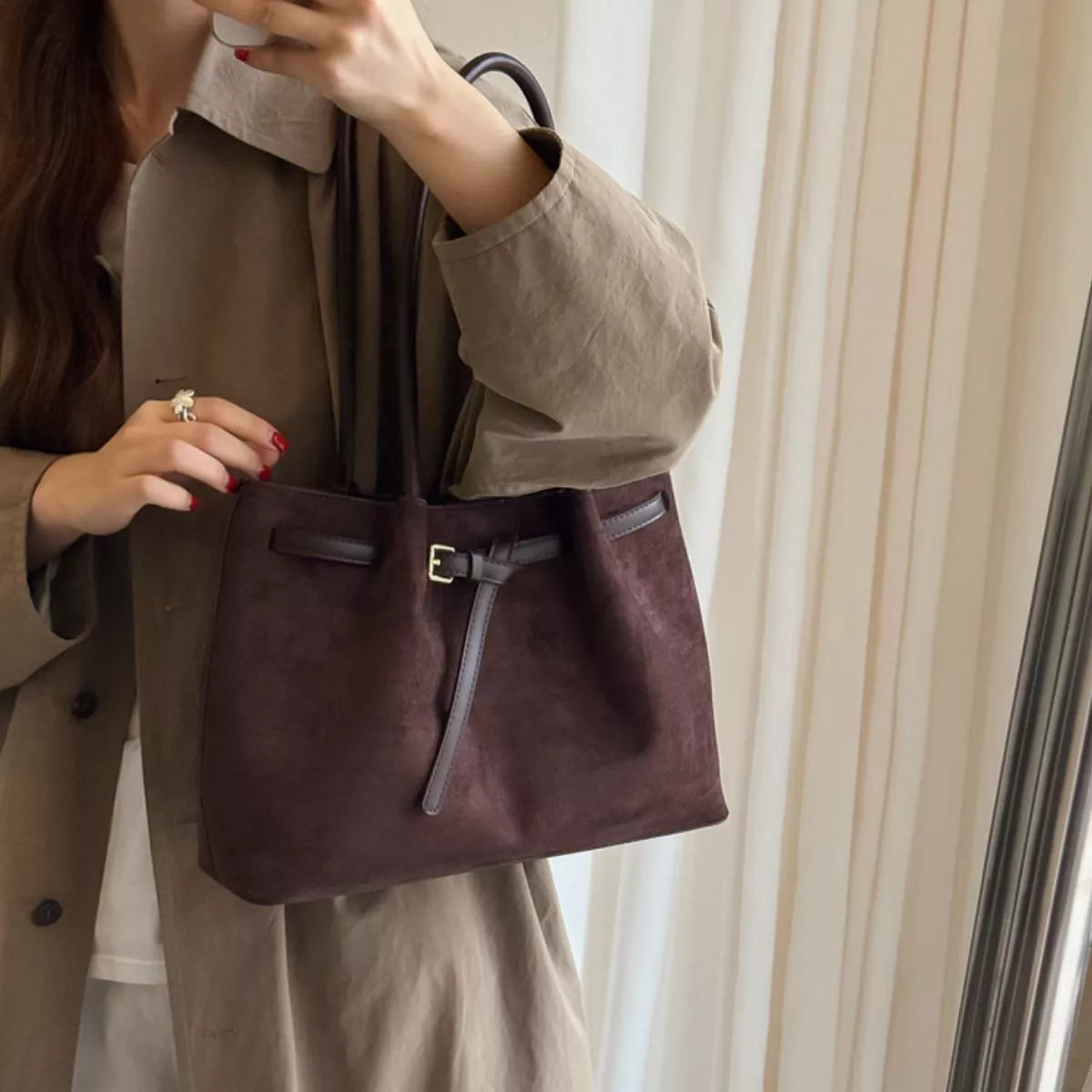 Dark brown suede shoulder bag with front buckle strap detail and zippered top