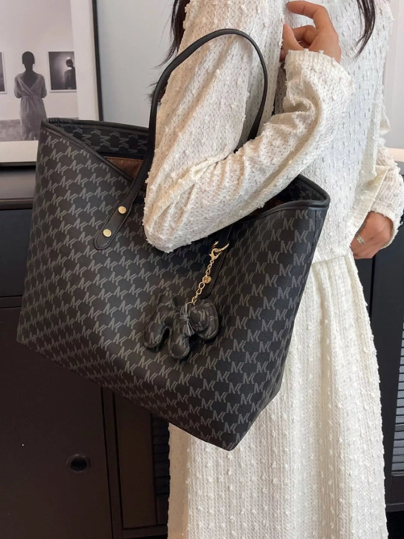 Dark monogram vegan leather tote with wide opening, top handles, and chain charm
