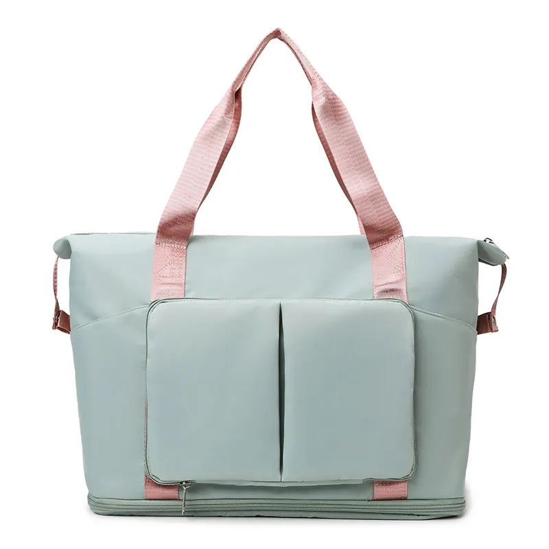 Sage green travel duffel bag with front organizer pocket, top handles, and side carry straps.