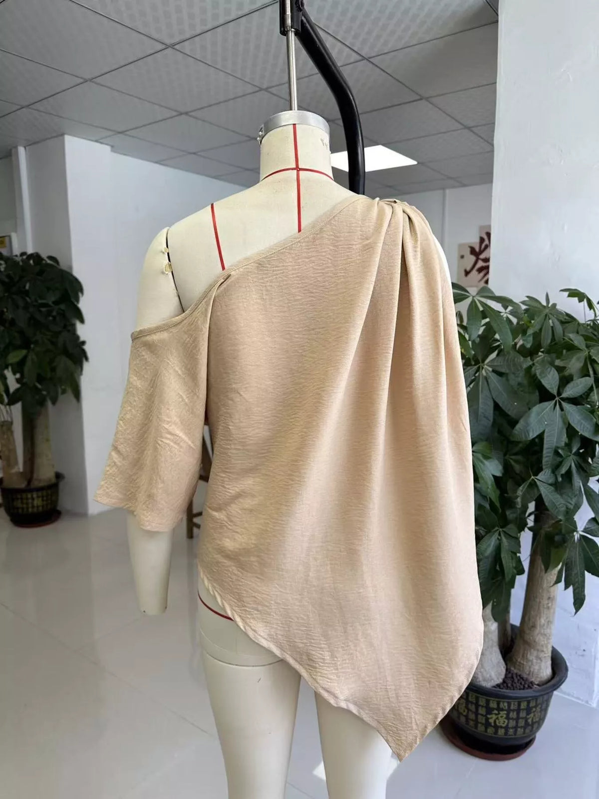 Khaki one-shoulder blouse with knotted back and loose drape, asymmetrical hemline