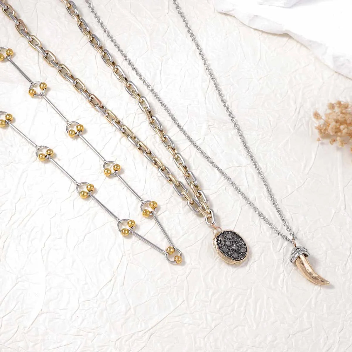 Layered chain necklaces with bead-link strands and round dark pendant, horn charm