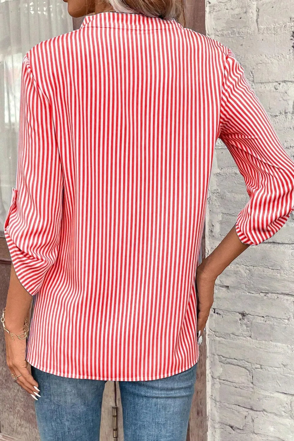 Back view of red and white striped shirt with roll-tab sleeves and buttoned back yoke