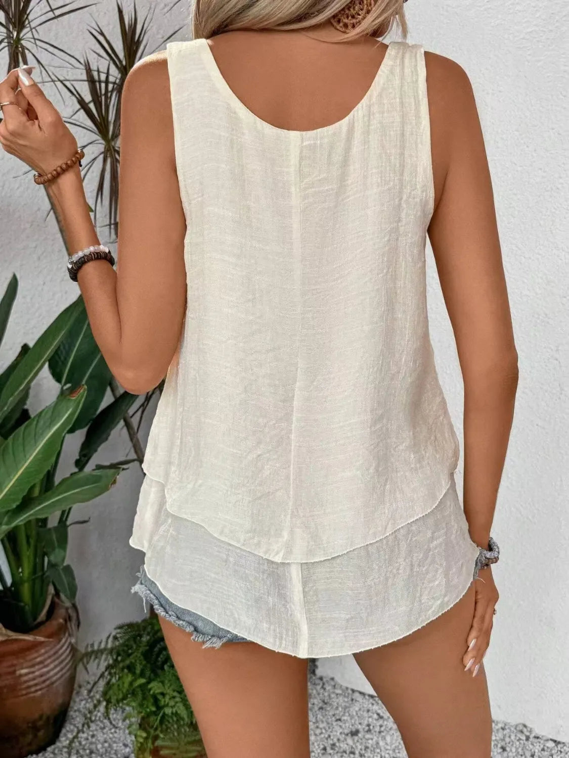 Cream wide-strap layered tank top from the back with open neckline cut and tiered hem.