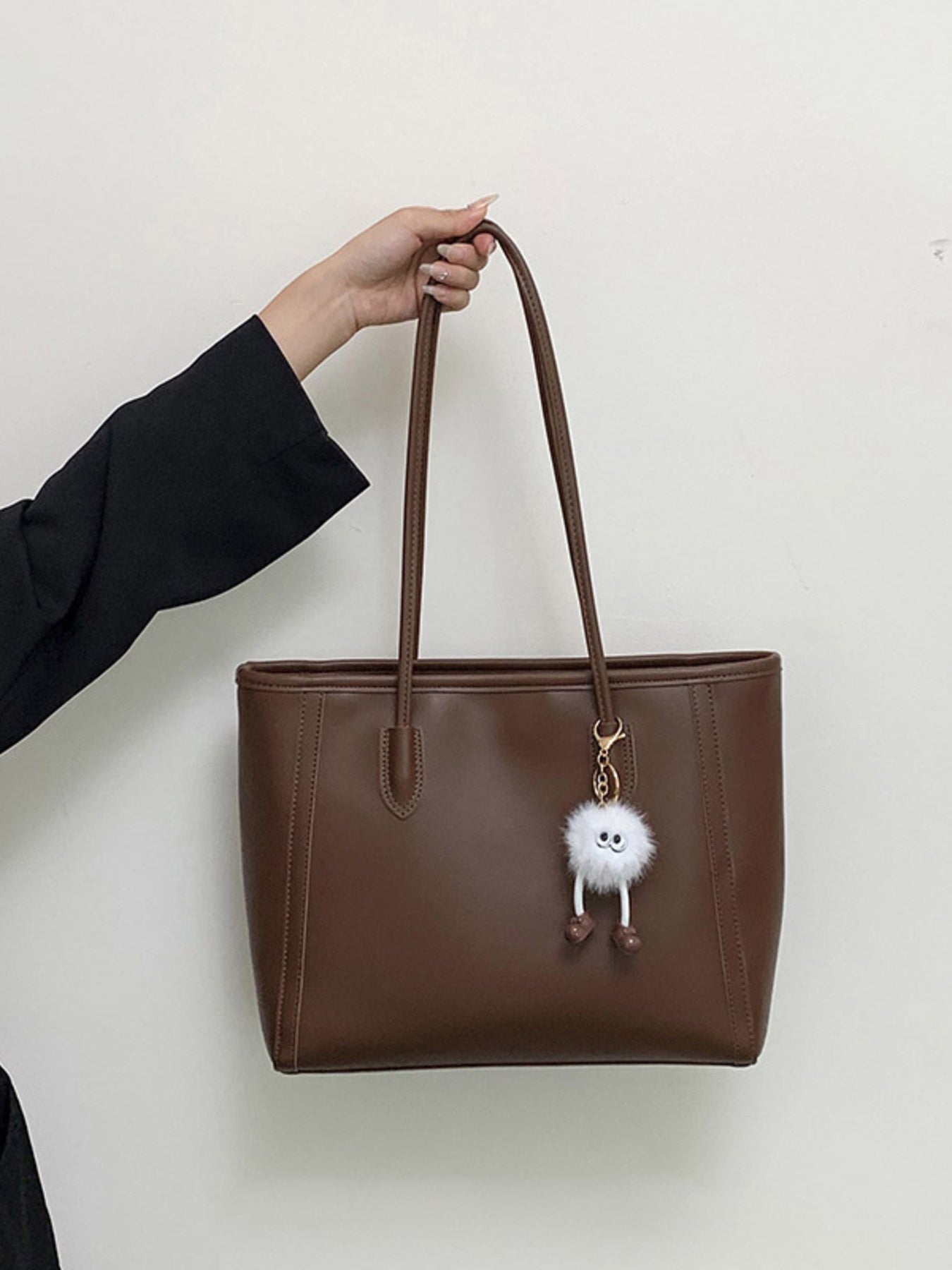 Brown PU leather shoulder bag, large size with two long handles and a white fluffy charm.