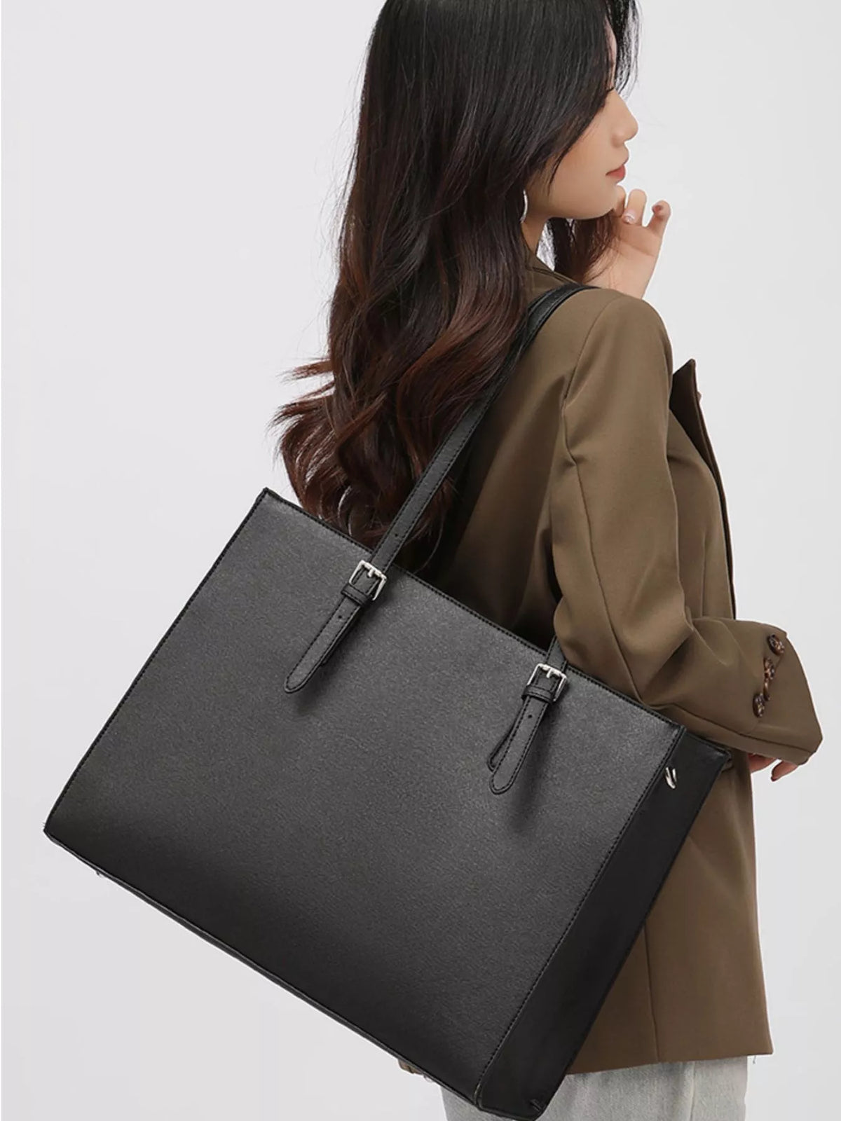 Black large tote bag with dual handles and front buckle accents; open top view.
