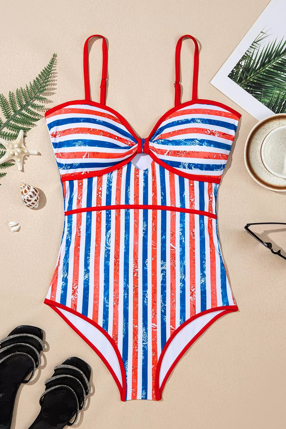 One-piece swimsuit flat lay, red straps, vertical blue-white stripes with knotted detail