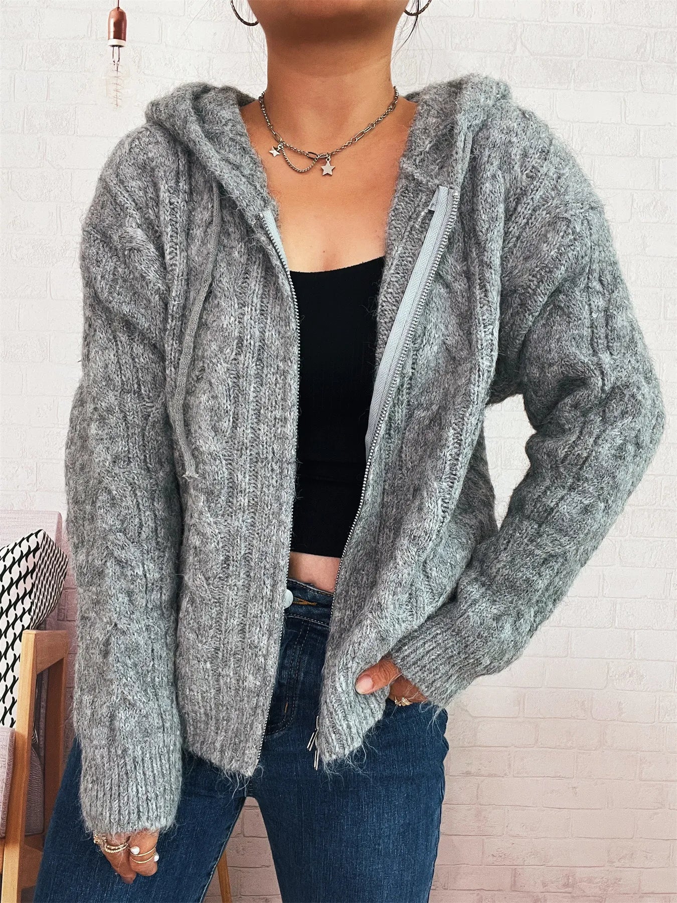 Gray cable knit hooded zip-up cardigan with long sleeves and open front zipper detail.