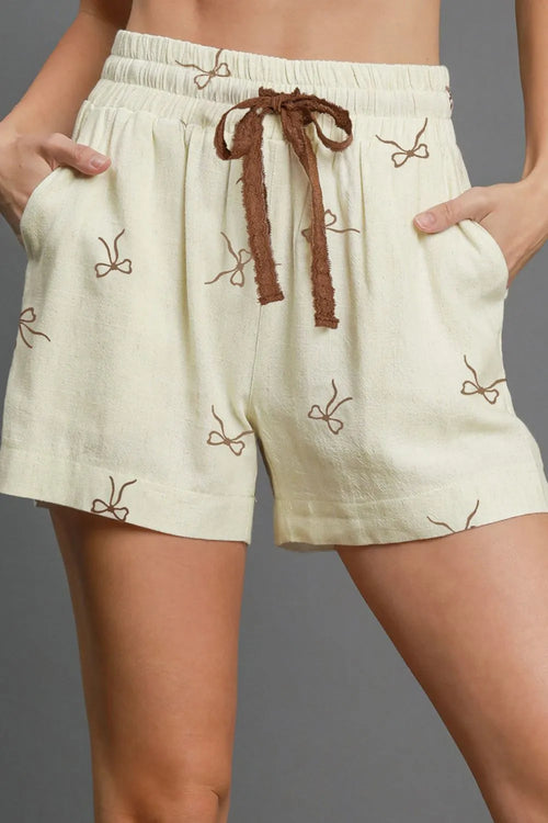 Cream casual shorts with brown bow drawstring and small bow-pattern embroidery