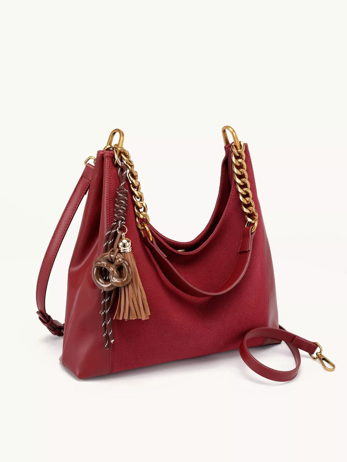 Wine red suede shoulder bag with gold chain strap, tassel charm, and long strap.