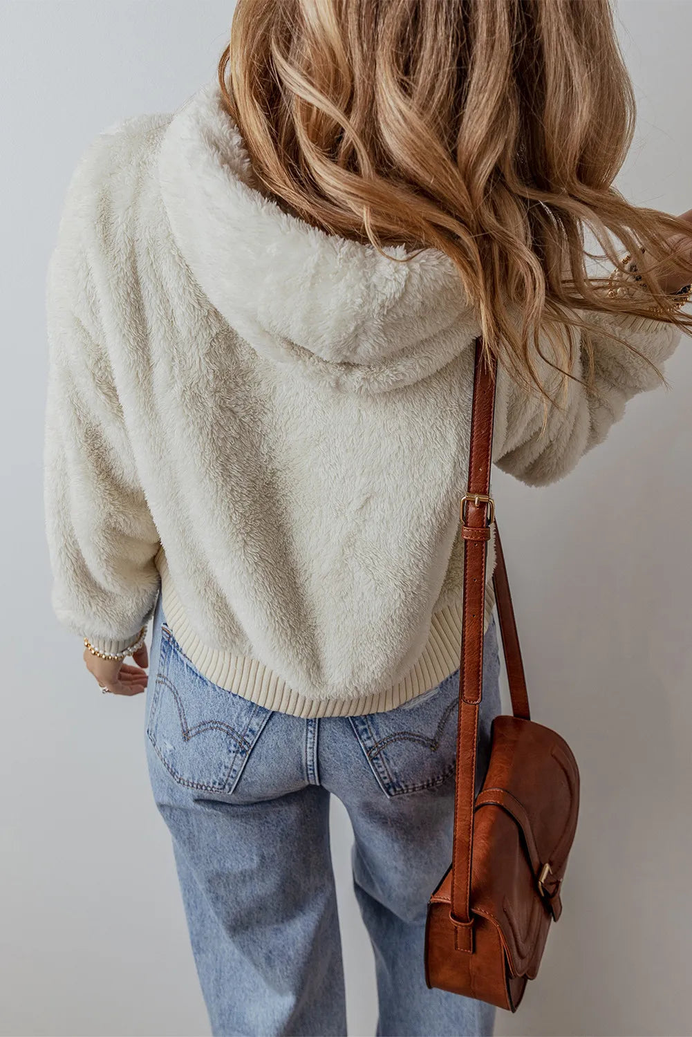 Beige fuzzy hoodie with adjustable hood, dropped shoulders, ribbed hem, worn with jeans