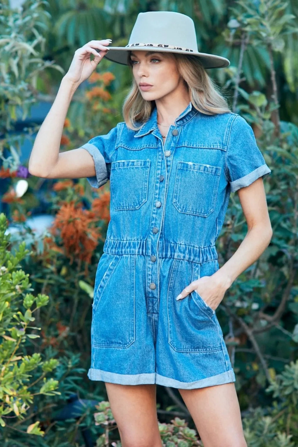 Light blue denim romper with elastic waist, button-up front, patch pockets, short sleeves