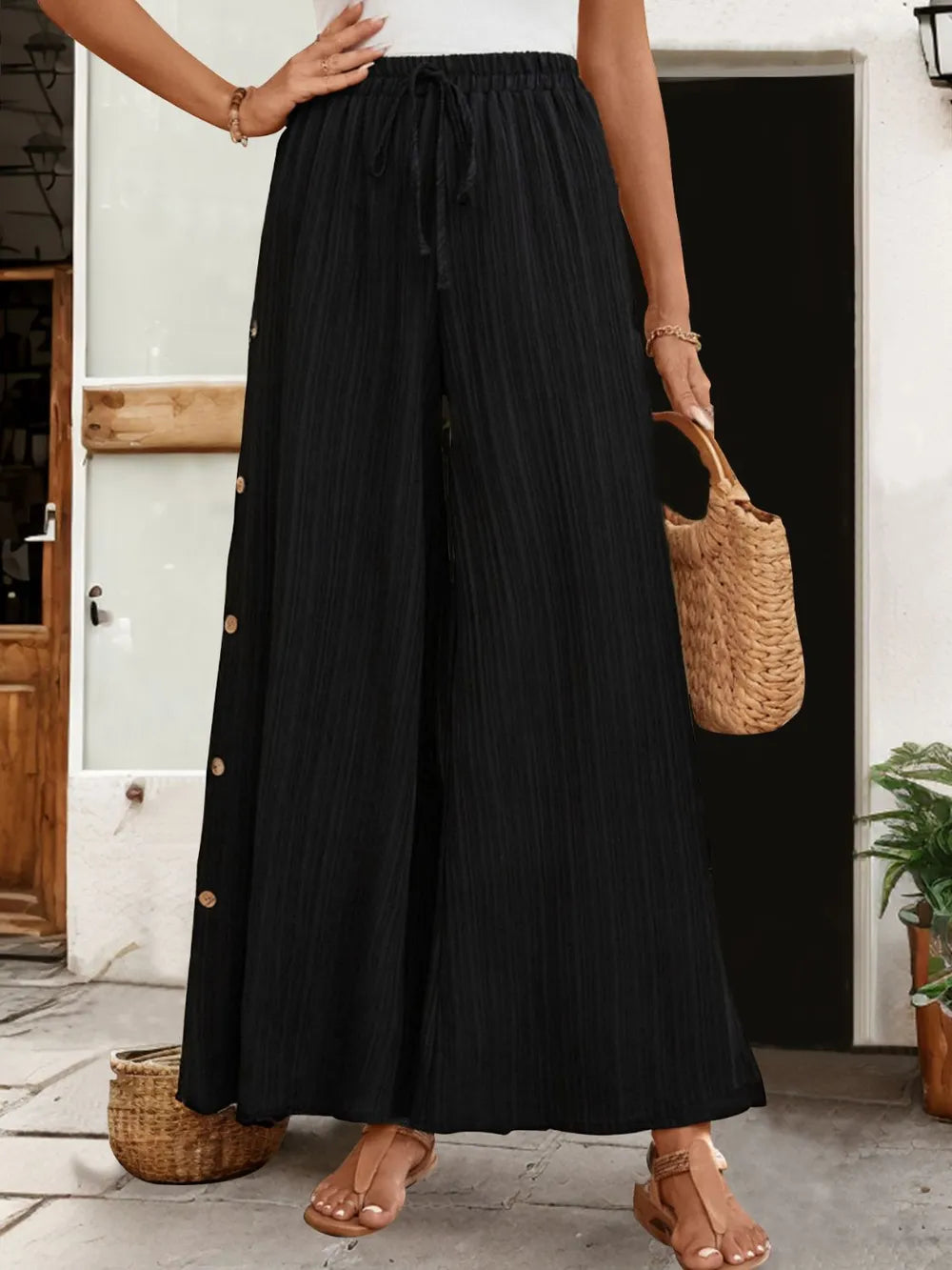 Tied slit wide-leg pants in black with elastic waistband and long wide legs, side slit detail