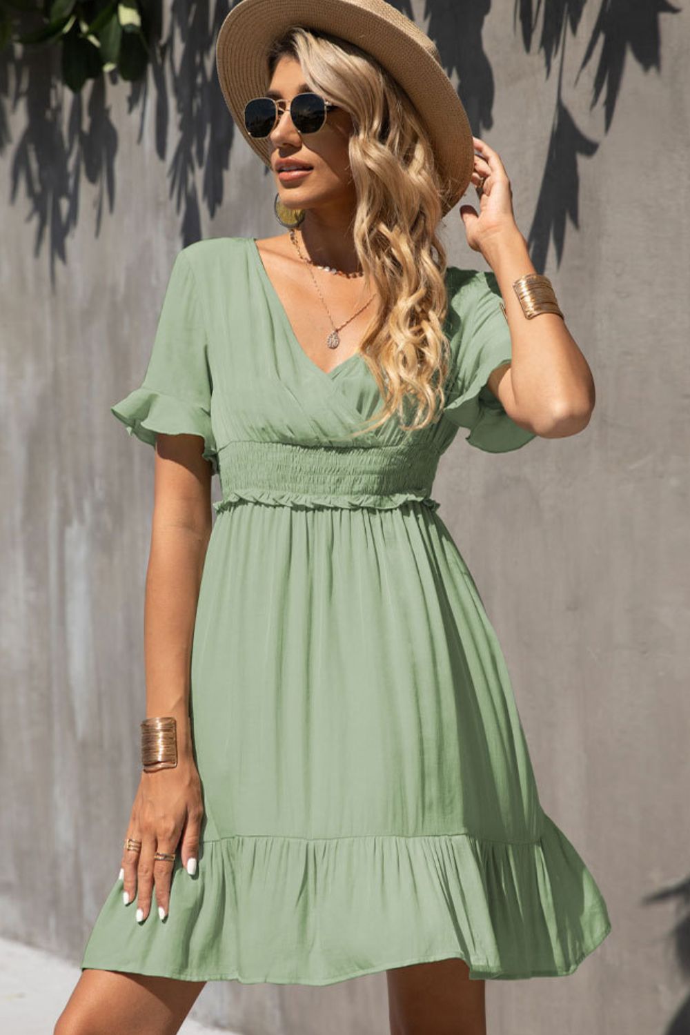 Light green smocked-waist V-neck dress with tiered ruffle hem and flutter sleeves.
