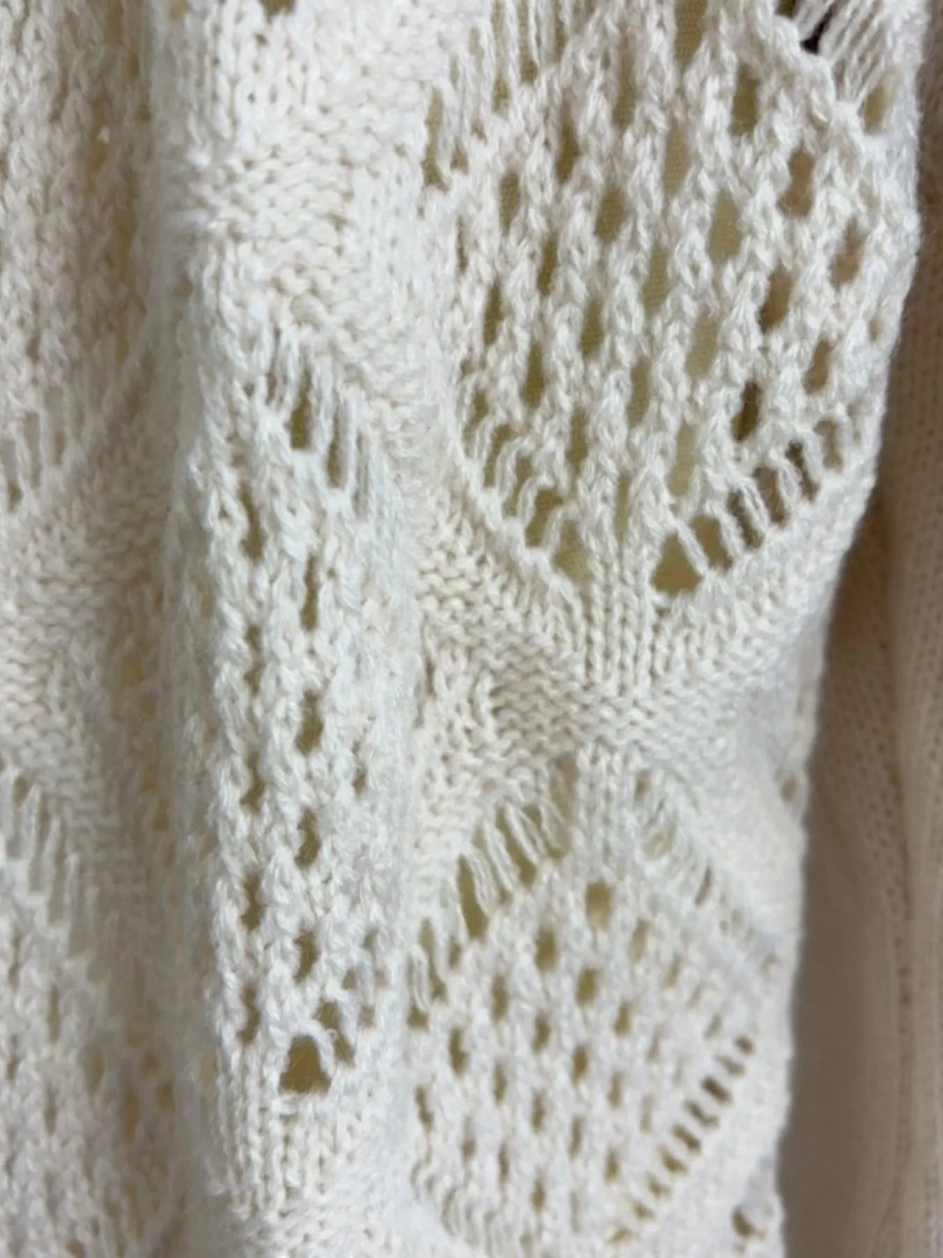 Knitted hollow-out pattern on sweater dress sleeve, white textured fabric