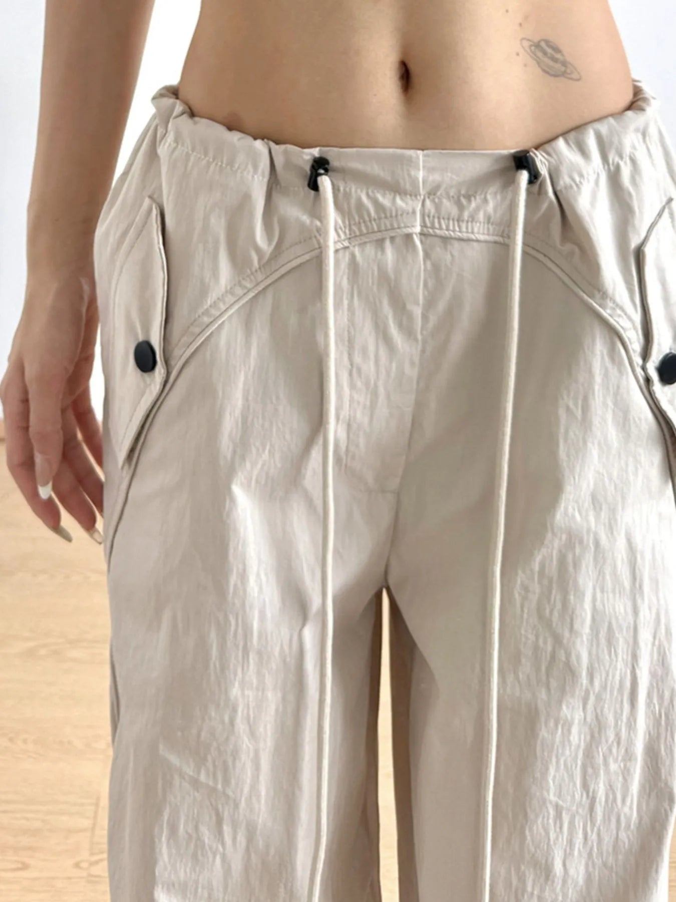 Beige wide-leg drawstring pants with elastic waist, side seams, and two draw ties
