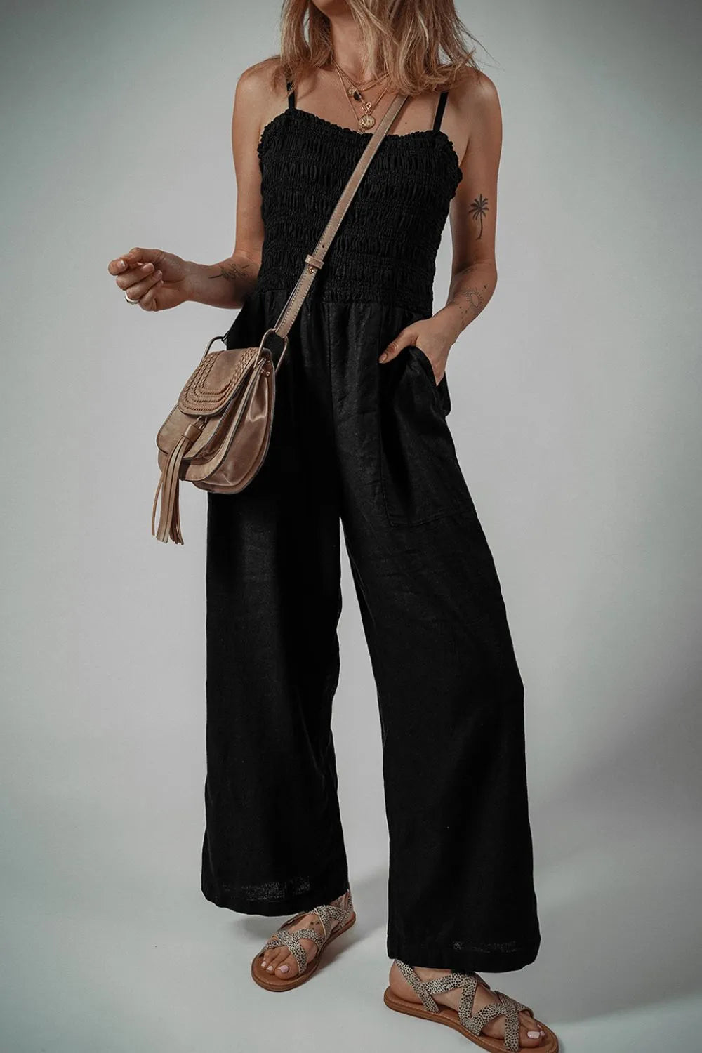 Black smocked spaghetti strap wide-leg jumpsuit with tiered bodice and wide pant legs