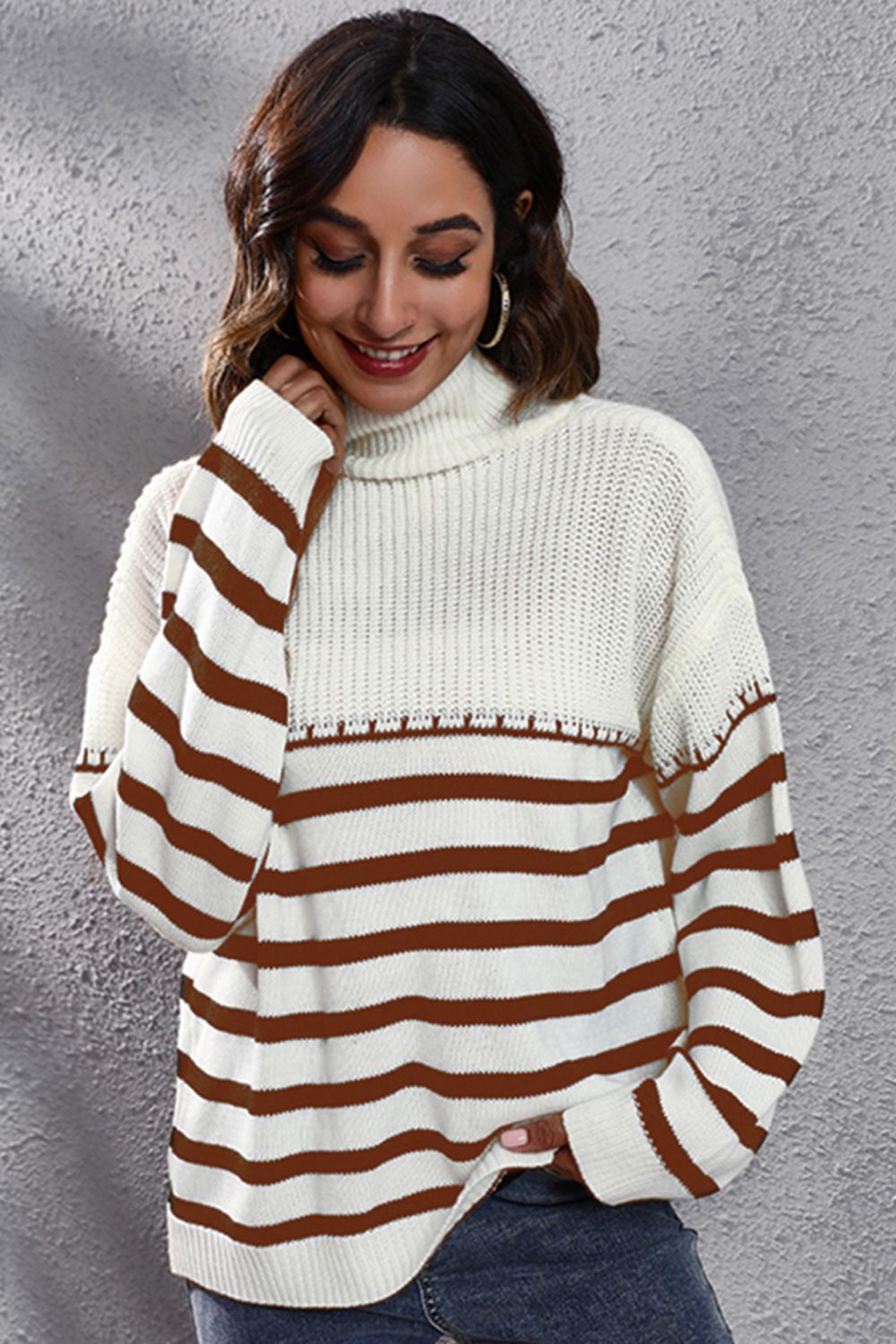 White knit turtleneck drop-shoulder sweater with brown and white horizontal stripes, side view