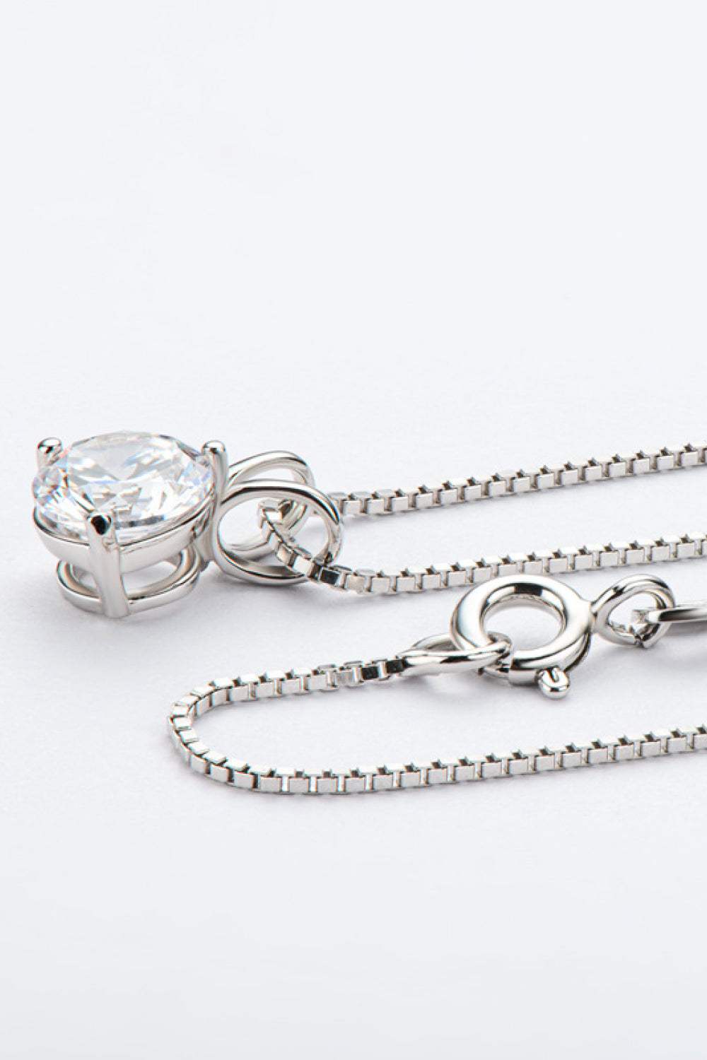 Silver-tone pendant necklace with round moissanite stone, bail detail, and link chain