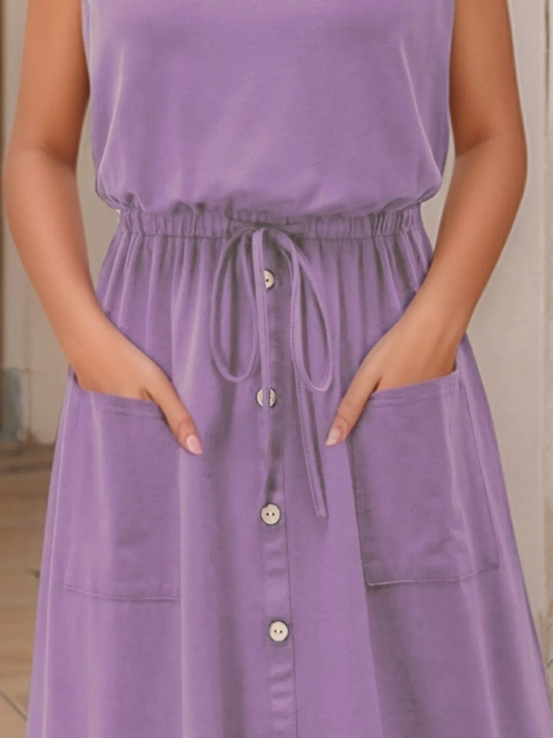 Tank dress in purple, sleeveless with drawstring waist, button-front and pockets.