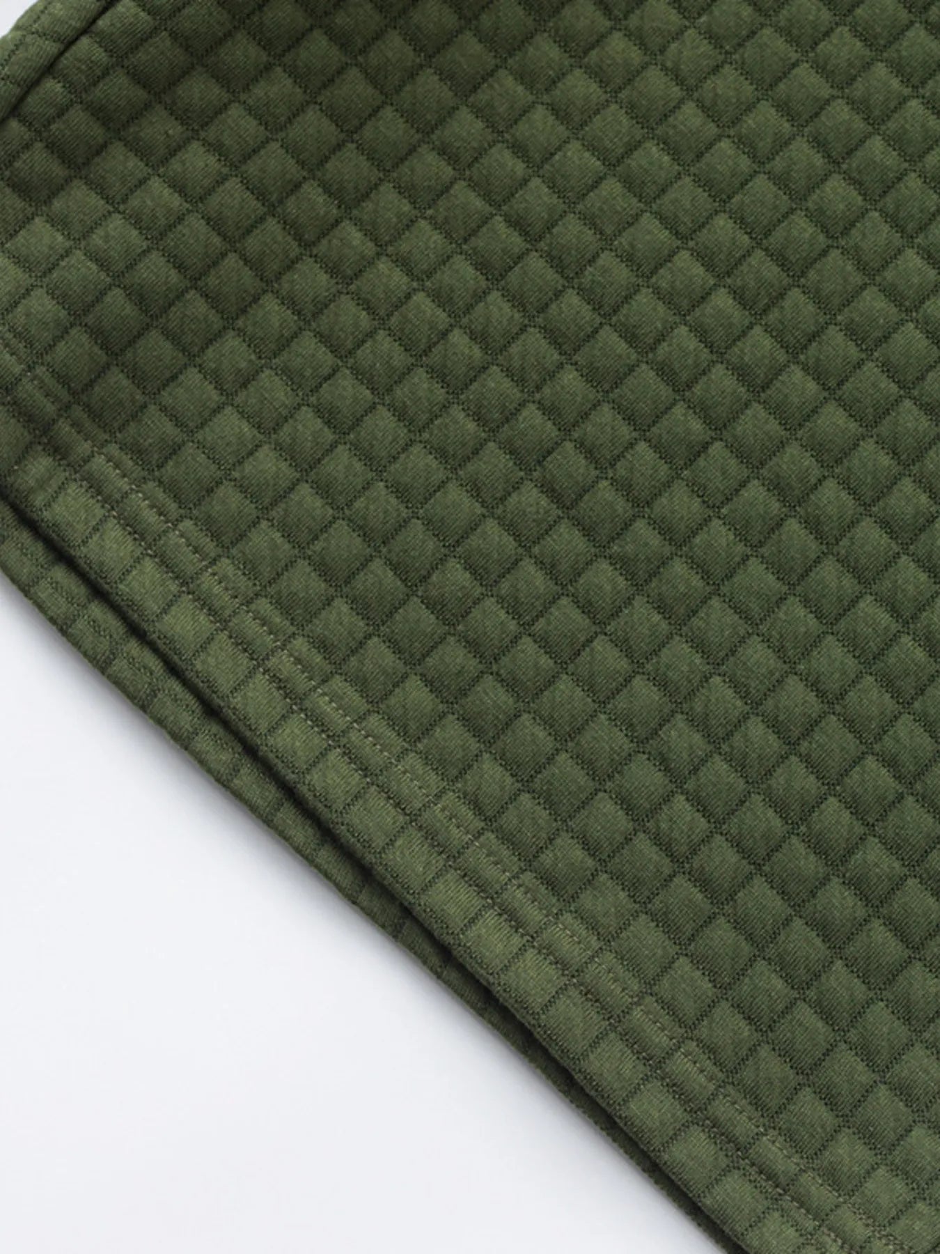 Dark green textured knit fabric with small raised square pattern, shorts edge detail