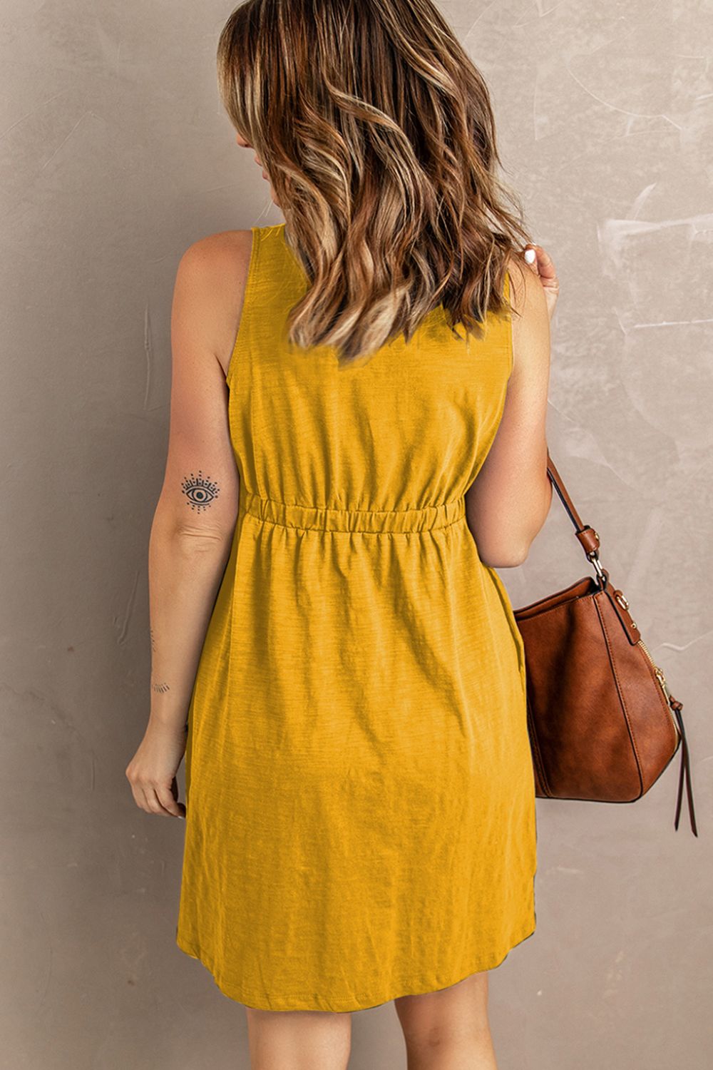 Sleeveless mini dress in mustard yellow with gathered waist and button back detail
