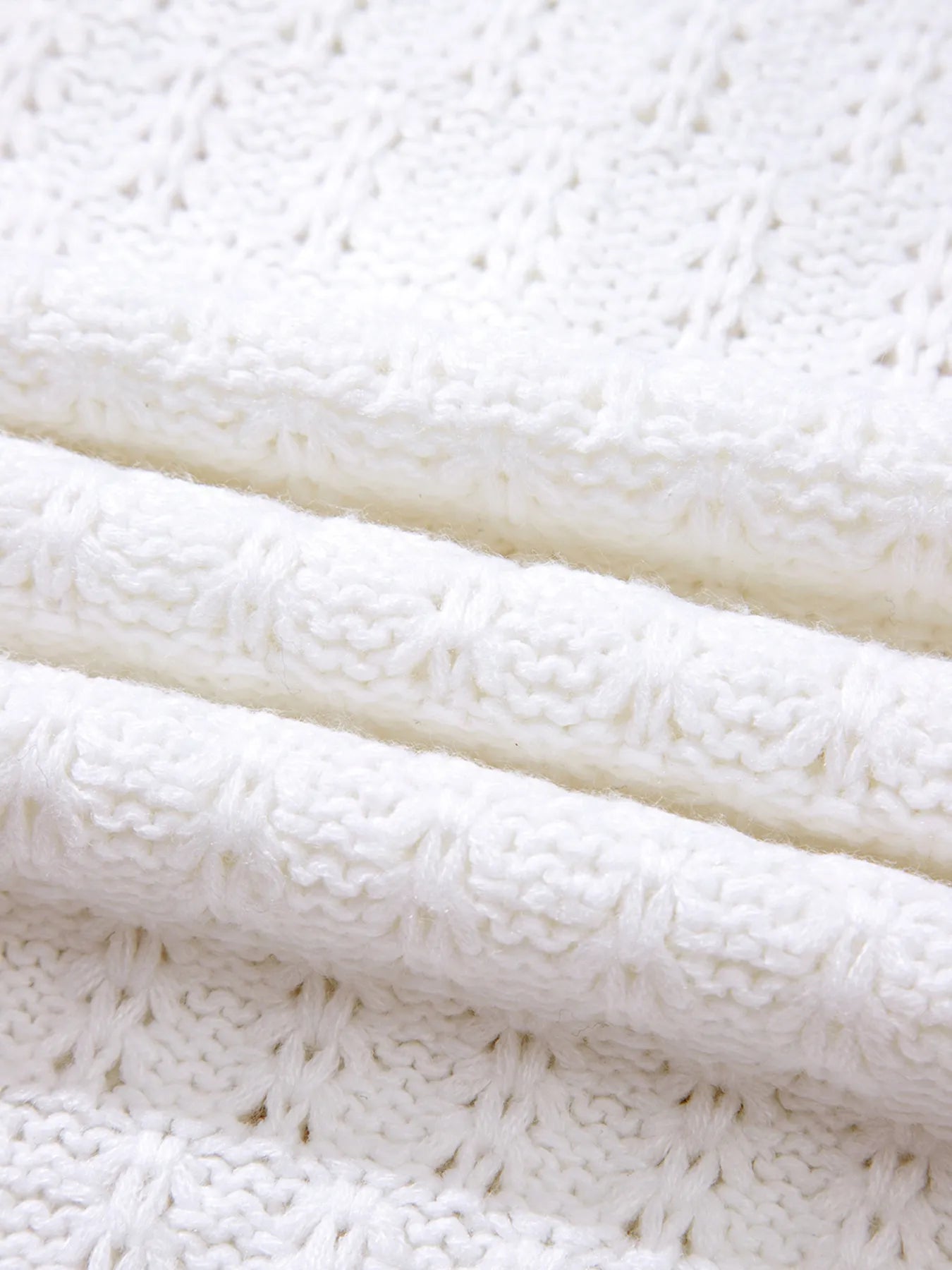 White ribbed knit sweater hem with textured cable-like stitch
