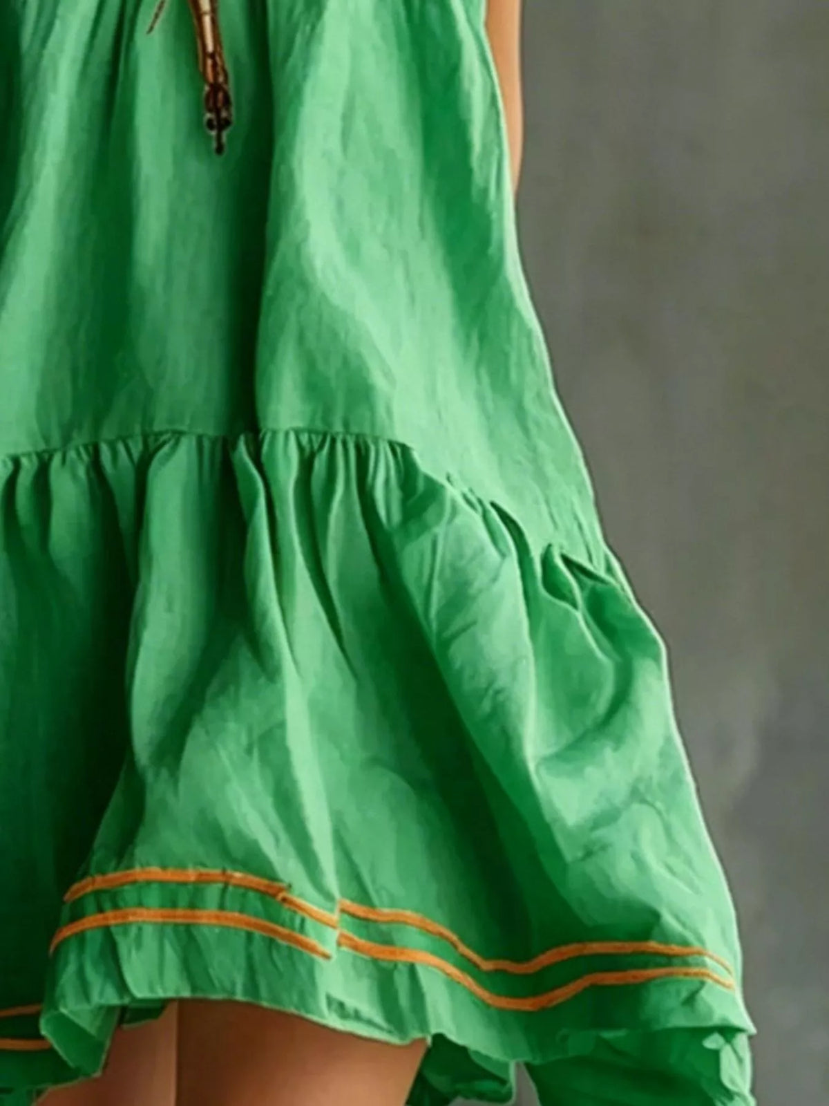 Green sleeveless tiered ruffle mini dress detail with orange-trimmed lower tier