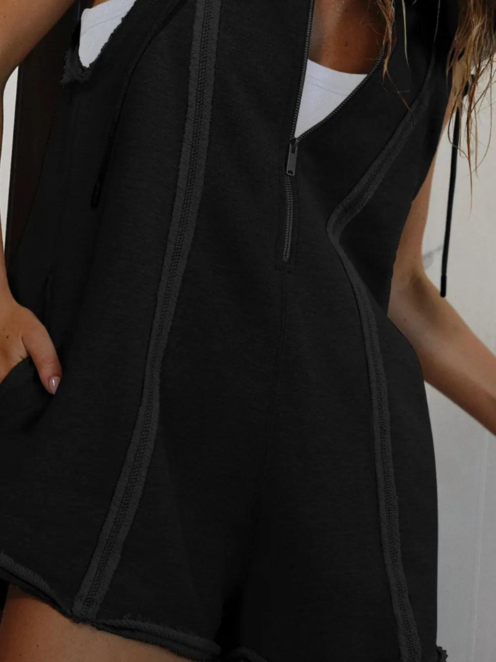 Black half-zip hooded sleeveless romper with prominent front zipper and panel seams